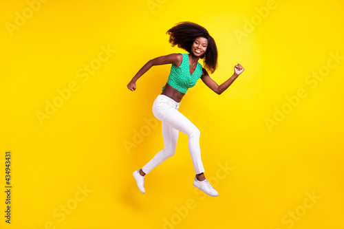 Full length body size photo young girl jumping running on meeting smiling cheerful isolated vivid yellow color background