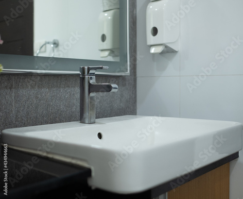 The stainless steel faucet is turned off and the white ceramic basin looks luxury.