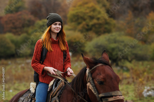 woman hiker with backpack rides a horse friendship travel mountains