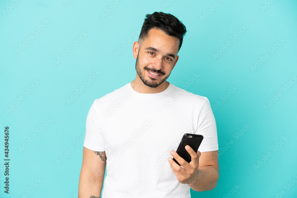 Young caucasian man isolated on blue background using mobile phone Young caucasian man isolated on blue background using mobile phone