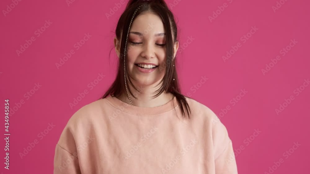 A happy young teenager girl is doing winner gesture while standing isolated over pink wall in the studio A happy young teenager girl is doing winner gesture while standing isolated over pink wall in the studio