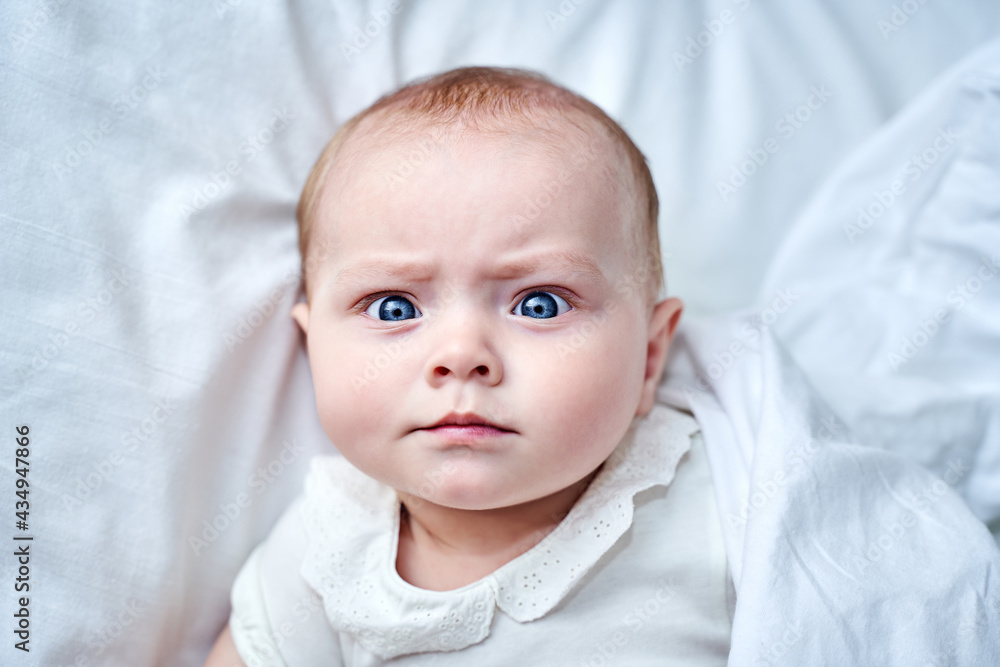 a small child of 6 months with blue eyes lies on a white background a small child of 6 months with blue eyes lies on a white background