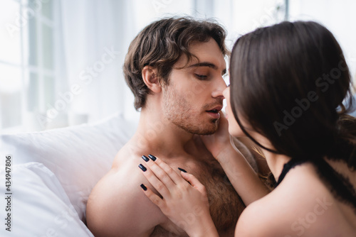 Blurred woman kissing sexy boyfriend on pillows