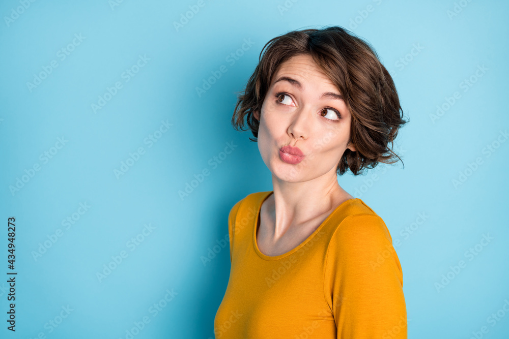 Portrait of nice pretty brunette lady look empty space wear yellow shirt isolated in vivid blue color background Portrait of nice pretty brunette lady look empty space wear yellow shirt isolated in vivid blue color background