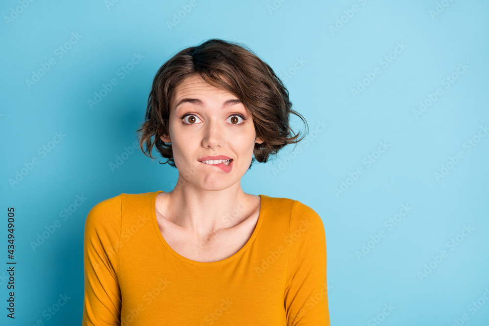 Photo of nice impressed brunette lady bite lips wear yellow shirt isolated in vivid blue color background