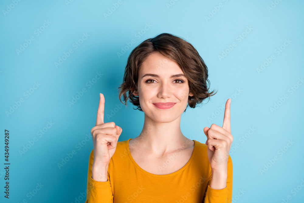 Portrait of young happy positive good mood lovely charming girl point finger up copyspace isolated on blue color background Portrait of young happy positive good mood lovely charming girl point finger up copyspace isolated on blue color background