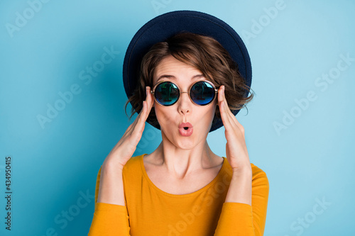 Photo portrait of amazed shocked woman in sunglass wearing shirt headwear isolated on bright blue color background photo