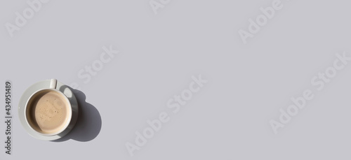 White cup of coffee on gray background with place for text. Minimal concept