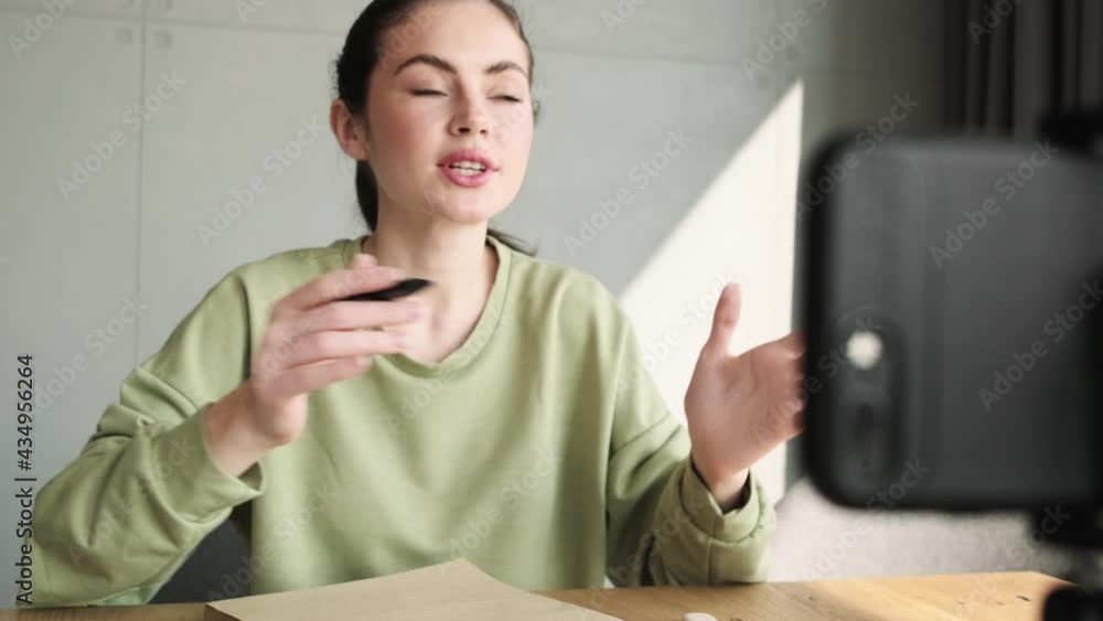 A happy woman talking by video call on the phone and actively gesturing while sitting at the table in the room A happy woman talking by video call on the phone and actively gesturing while sitting at the table in the room