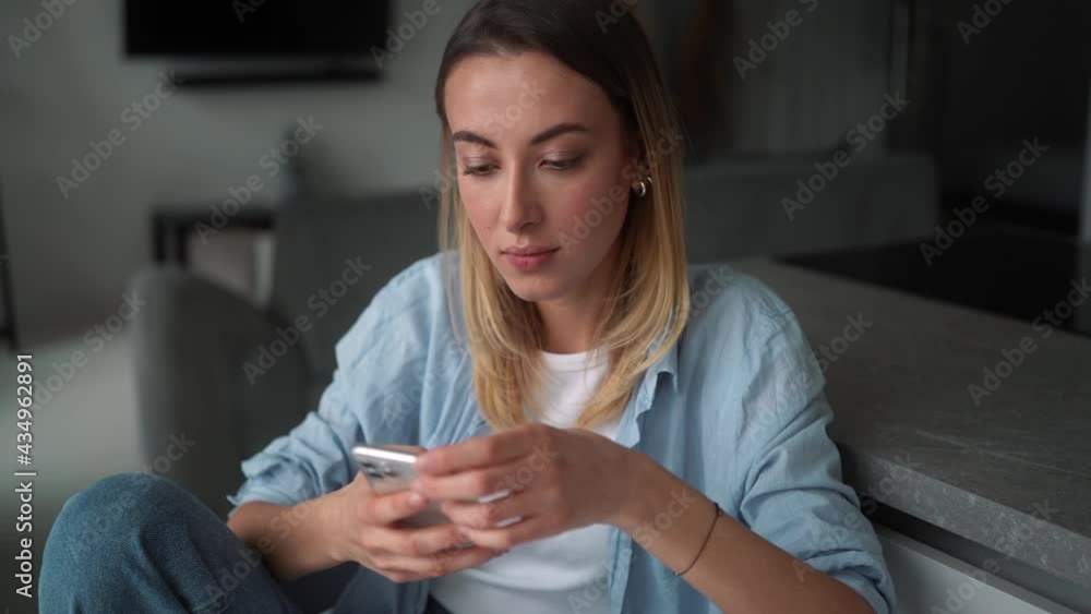 The brooding woman leafing through the tape on the phone while sitting at the table in the room The brooding woman leafing through the tape on the phone while sitting at the table in the room