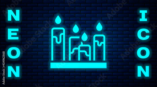 Glowing neon Burning candle icon isolated on brick wall background. Cylindrical aromatic candle stick with burning flame. Happy Halloween party. Vector