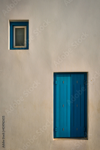 Greek architecture abstract background - whitewashed house with blue painted window blinds © Dmitry Rukhlenko