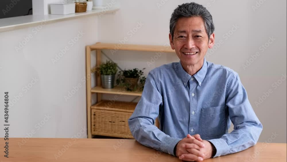 自宅のリビングに笑顔で佇むシニア男性 自宅のリビングに笑顔で佇むシニア男性
