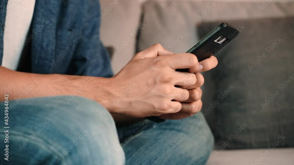 Close up of young man using mobilephone or smartphone on the sofa. searching, browsing, shopping online, social network. Close up of young man using mobilephone or smartphone on the sofa. searching, browsing, shopping online, social network.