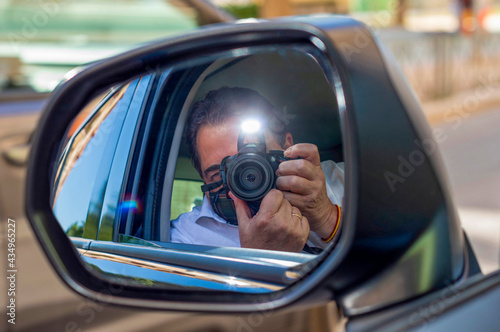MAN WITH MASK TAKING PHOTO FROM INSIDE THE CAR AND REFLECTED IN THE REAR VIEW MIRROR