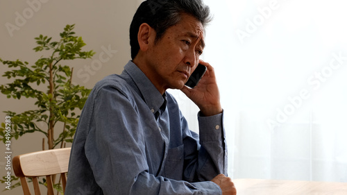 通話をしながら困り果てるシニア男性