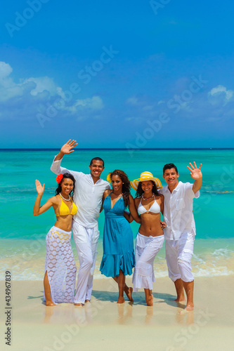 Girls and guys at the beach, standing on the seashore and waving, interracial, black, dressed in white outfits, fun couples on the beach