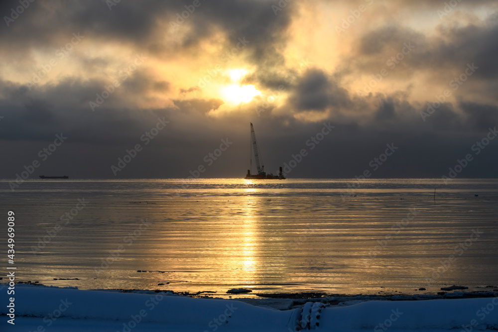 Beautiful sunset in Arctic sea. Barge with crane. Golden hour. Construction Marine offshore works. Dam building, crane, barge, dredger. Beautiful sunset in Arctic sea. Barge with crane. Golden hour. Construction Marine offshore works. Dam building, crane, barge, dredger.