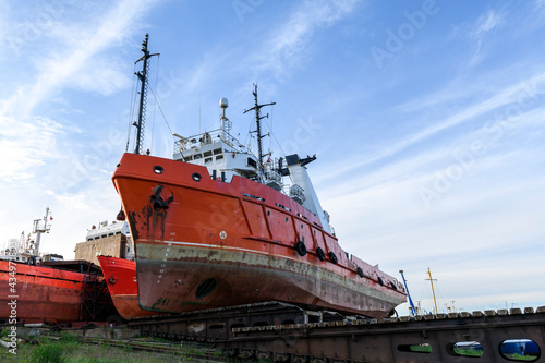 Tug vessel ashore on ship repairing yard. Summer time.