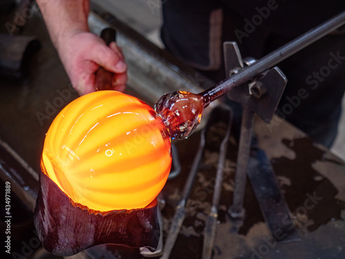 Konstfotografi Glassblowing crafter rounds the hot-striped vase  with wet woode tool