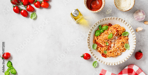 Tasty appetizing classic italian spaghetti pasta with tomato sauce,  parmesan cheese and fresh basil leaves.  Light gray stone background, top view. Space for text