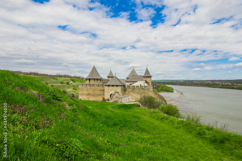 View of old castle Hotin near the river. Khotyn Fortress - medieval castle on yellow autumn hills. Ukraine, Eastern Europe. The architecture of the Middle Ages in our time.