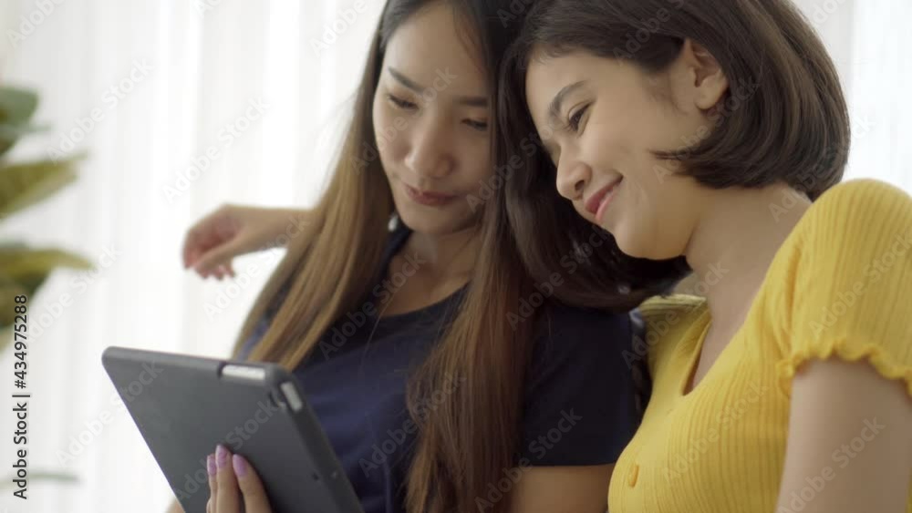 4K Young beautiful Asian couple love friend woman looking at tablet and touch hand on bedroom at home which smiling and felling happy, LGBT woman love Travelling summer vacation trip concept. 4K Young beautiful Asian couple love friend woman looking at tablet and touch hand on bedroom at home which smiling and felling happy, LGBT woman love Travelling summer vacation trip concept.