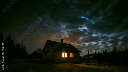 Time lapse with small house in night forest under cloudy sky with moon. 