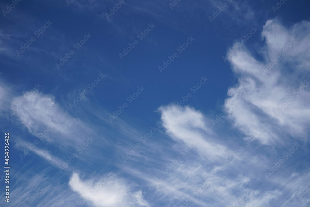 Beautiful summer blue sky with white feather clouds, natural background for banner.Soft spindrift clouds.Natural cloudy sky backdrop.Spring clouds texture