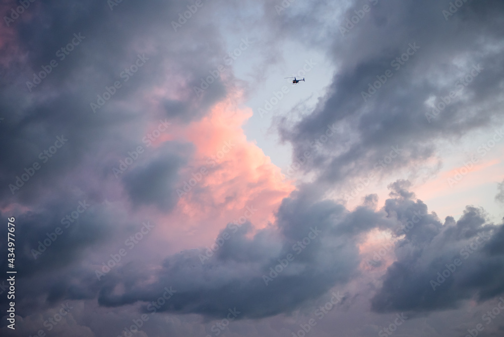 Heavenly view of pastel pink and purple clouds with single object helicopter flying into the abyss. Artistic view of sky Heavenly view of pastel pink and purple clouds with single object helicopter flying into the abyss. Artistic view of sky