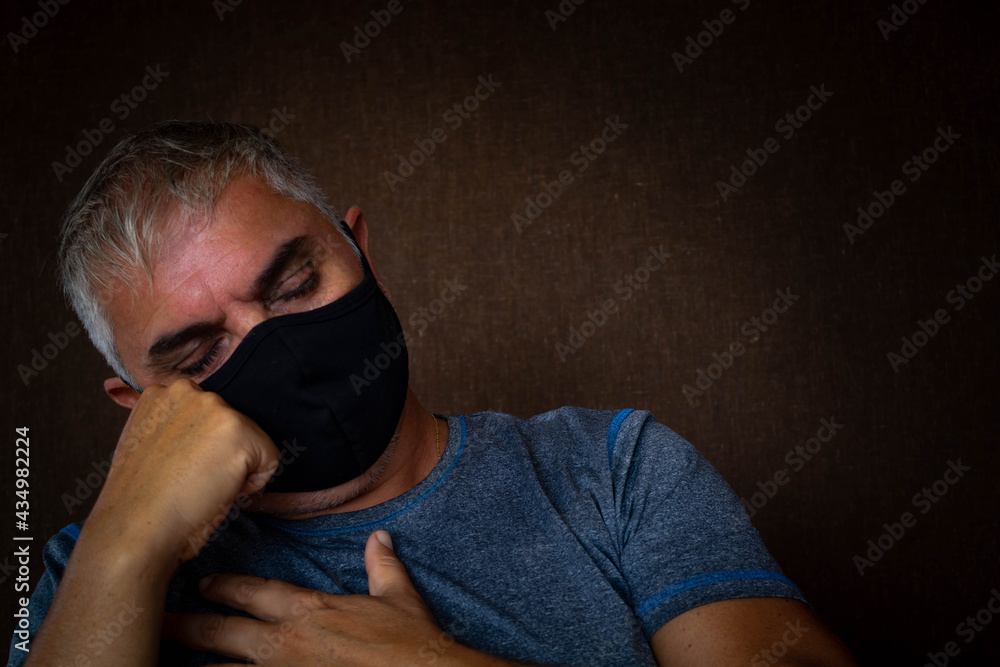 Obraz premium Middle-aged man with white hair and face mask in times of pandemic. With her head resting on his hand.
