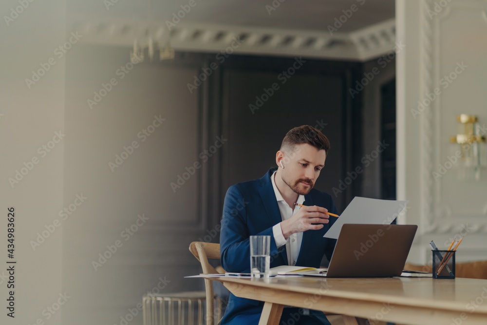Thinking business executive sitting at his desk in front of laptop and analyzing documents Thinking business executive sitting at his desk in front of laptop and analyzing documents