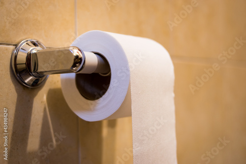 Closeup of a white toilet paper with an orange background in a bathroom
