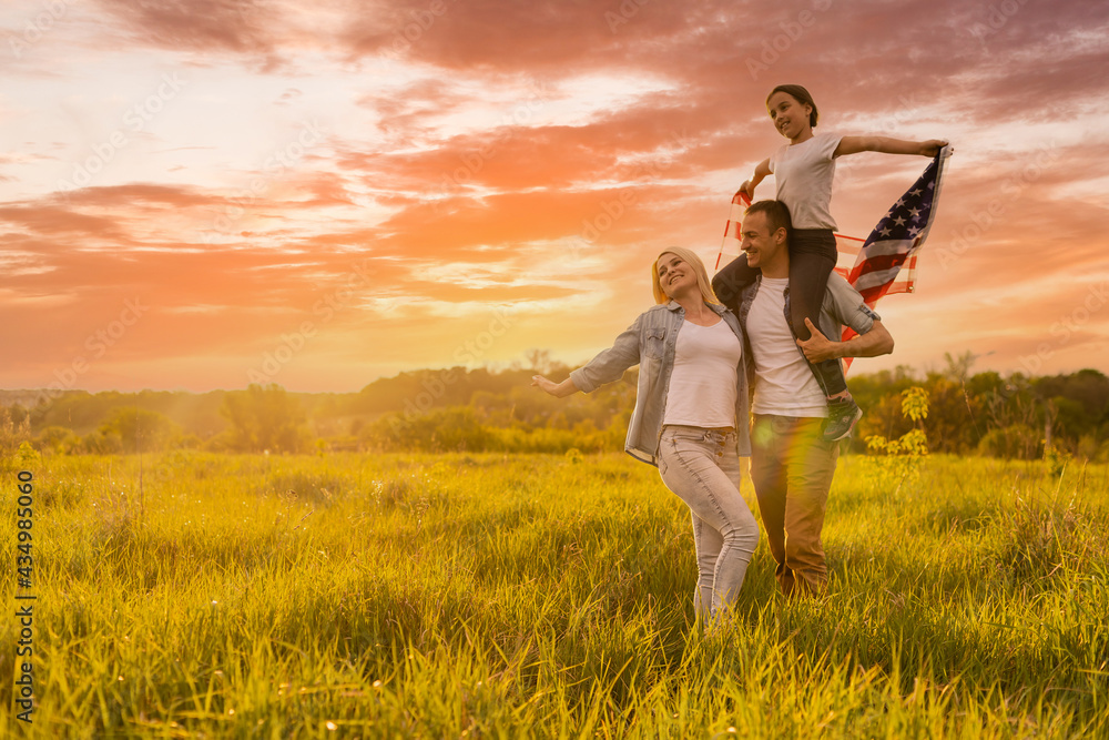 Patriotic holiday. Happy family, parents and daughters children girl with American flag outdoors. USA celebrate 4th of July. Patriotic holiday. Happy family, parents and daughters children girl with American flag outdoors. USA celebrate 4th of July.