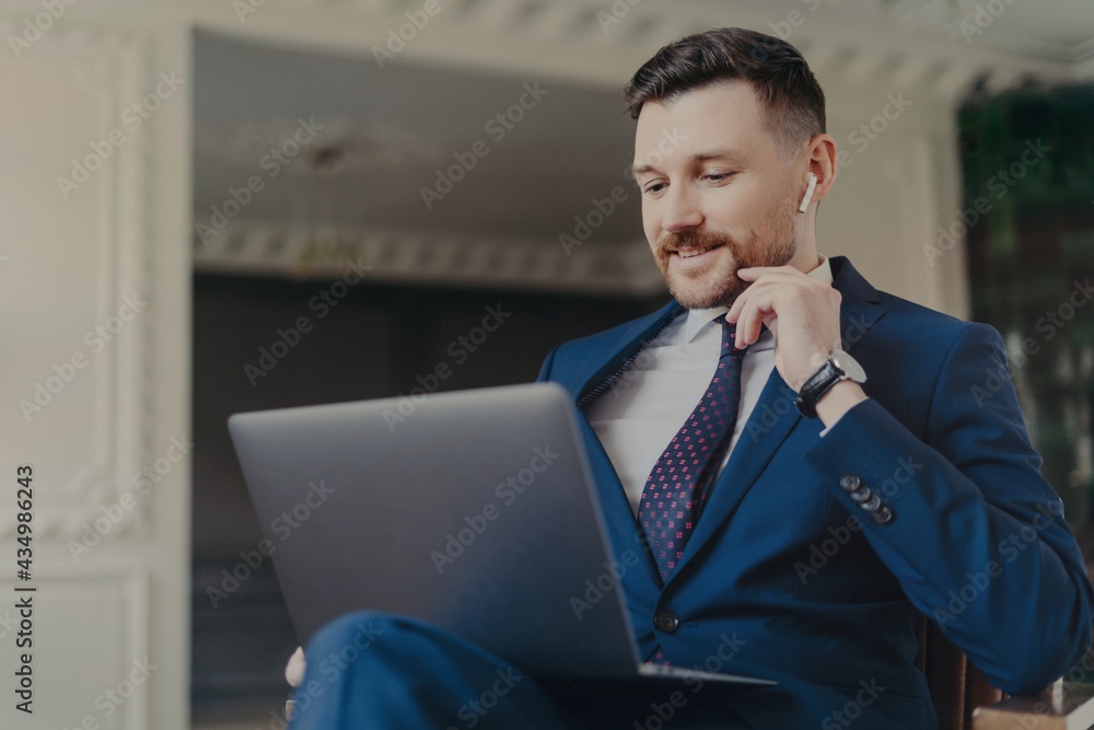 Young successful businessman having online meeting on laptop while sitting in office Young successful businessman having online meeting on laptop while sitting in office