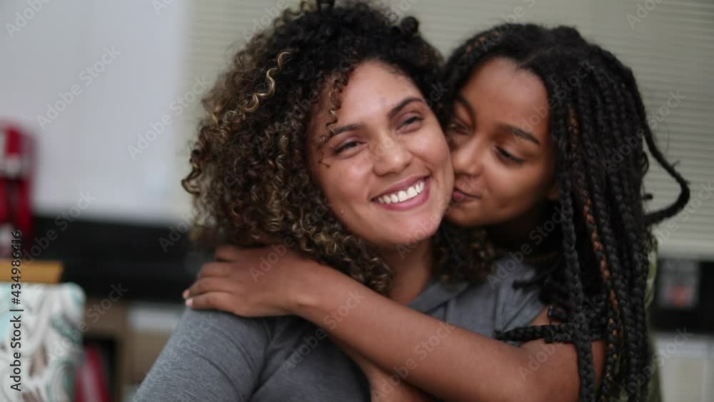 Daughter embracing and kissing mother. Black ethnicity Daughter embracing and kissing mother. Black ethnicity