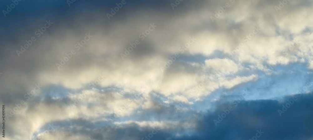 White and light gray clouds on the blue sky. On a clear sunny day, there are several high cumulus clouds against the backdrop of a clear, light blue sky. Clouds of different shapes and sizes.