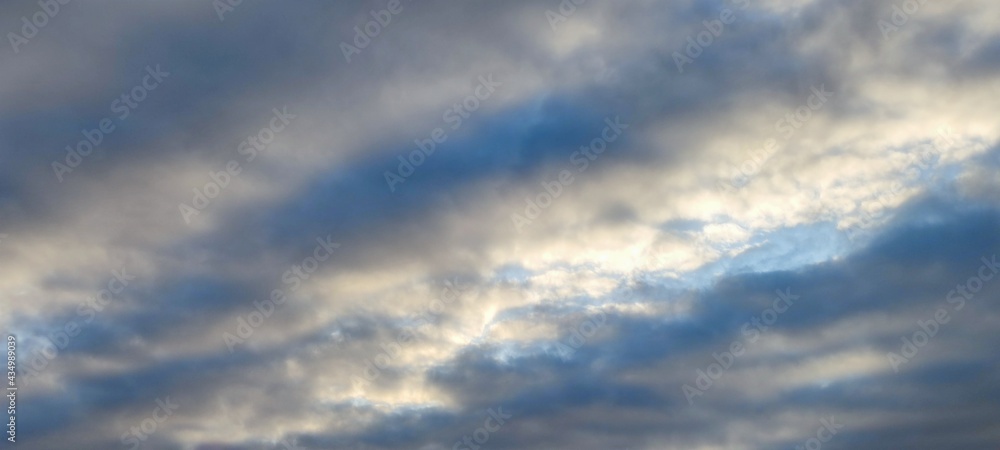 White and light gray clouds on the blue sky. On a clear sunny day, there are several high cumulus clouds against the backdrop of a clear, light blue sky. Clouds of different shapes and sizes.