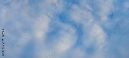 White and light gray clouds on the blue sky. On a clear sunny day  there are several high cumulus clouds against the backdrop of a clear  light blue sky. Clouds of different shapes and sizes.