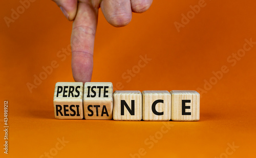 Persistence or resistance symbol. Businessman turns cubes, changes the word 'resistance' to 'persistence'. Beautiful orange background. Copy space. Business and persistence or resistance concept.