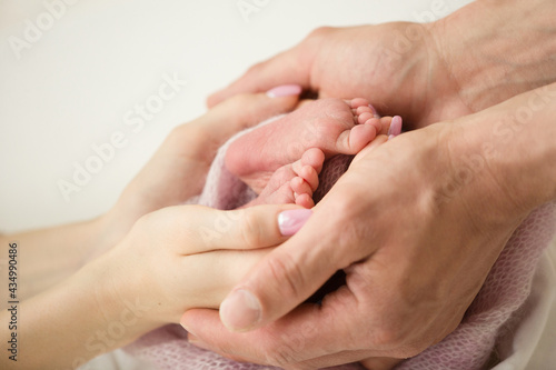 Children's feet in hold hands of mother and father. Mother, father and Child. Happy Family people concept.
