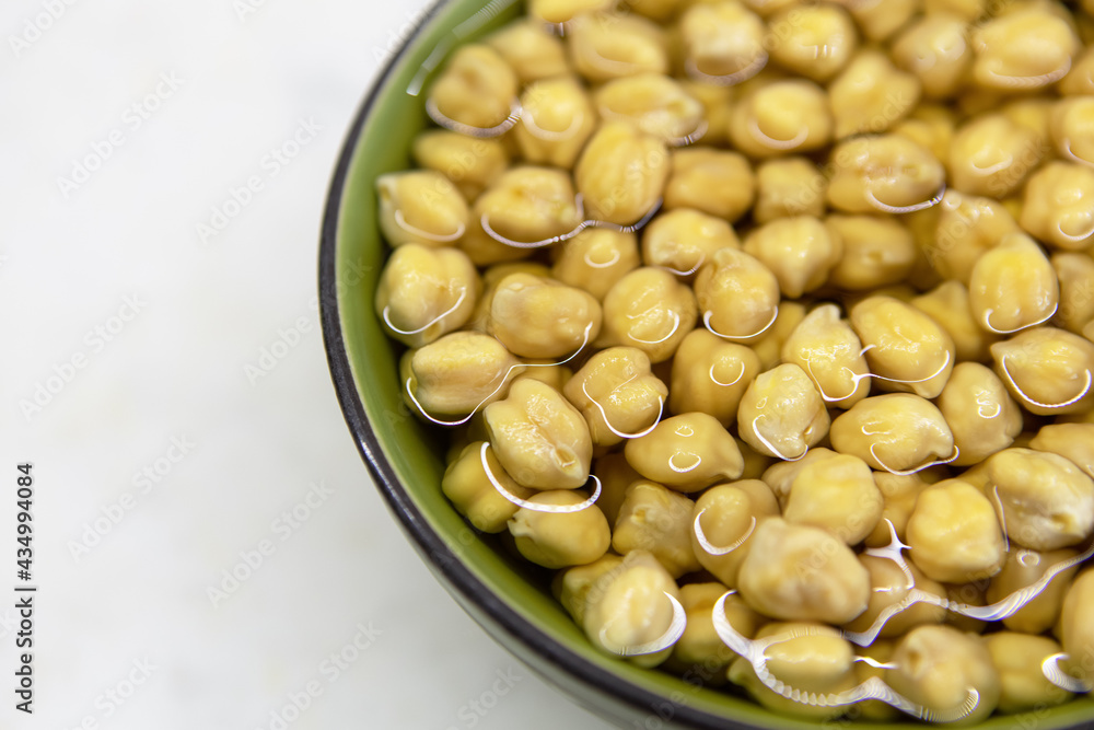 Chickpeas soaked in water, in bowl, on marble table. Concept of healthy eating, veganism, vegetarianism, meat and egg replacement. Prepare chickpeas before making hummus and other legume dishes Chickpeas soaked in water, in bowl, on marble table. Concept of healthy eating, veganism, vegetarianism, meat and egg replacement. Prepare chickpeas before making hummus and other legume dishes