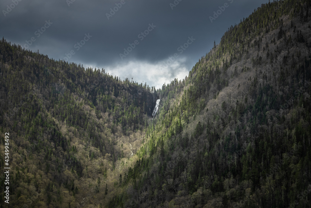 Fototapeta premium Amazing photo of a waterfall coming from the top of a mountain in Jacque cartier national park, Quebec, Canada