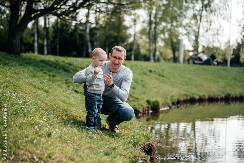 Fototapeta premium happy family on the bank near the river in summer in the park. Concept of family vacation in nature. dad and kids, father's day