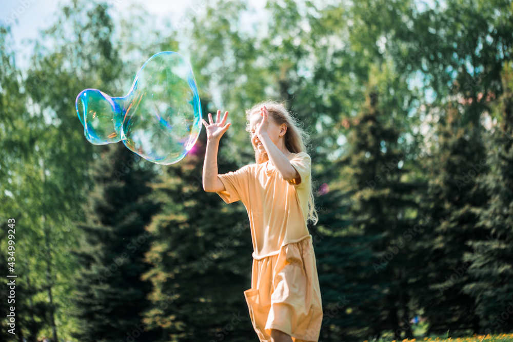 happy emotional sweet girl dancing and playing with soap bubbles enjoying a sunny day in the park. happy emotional sweet girl dancing and playing with soap bubbles enjoying a sunny day in the park.