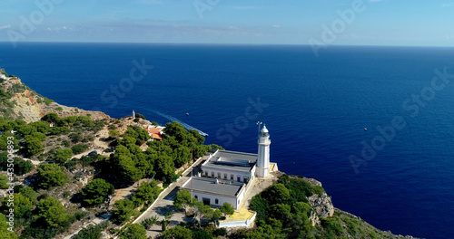 Lighthouse on the edge of a cliff with the Mediterranean Sea in the background, under the sunlight - aerial view with a drone 4K