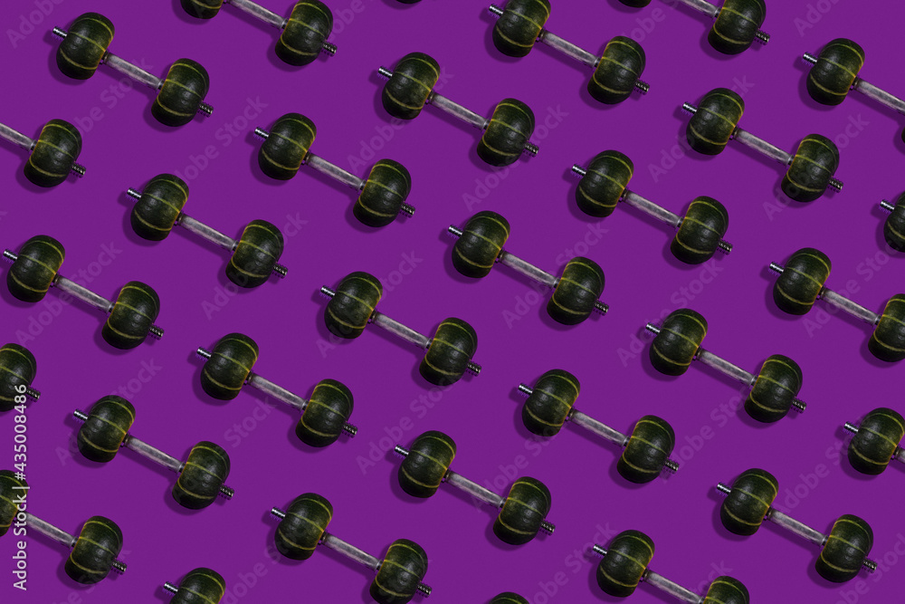 Creative layout made of dumbbells with a weight in the form of pumpkins, purple background, healthy lifestyle and sport concept Creative layout made of dumbbells with a weight in the form of pumpkins, purple background, healthy lifestyle and sport concept