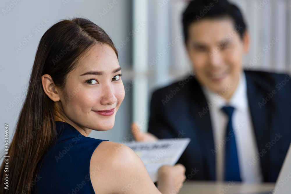 Young Asian man and woman smiling while sitting at table during job interview Young Asian man and woman smiling while sitting at table during job interview