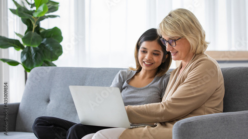 Young woman teaching mother to use laptop