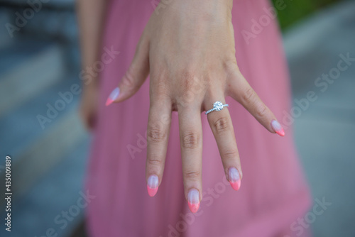 Engagement ring on female hand with girly pink tipped nails photo